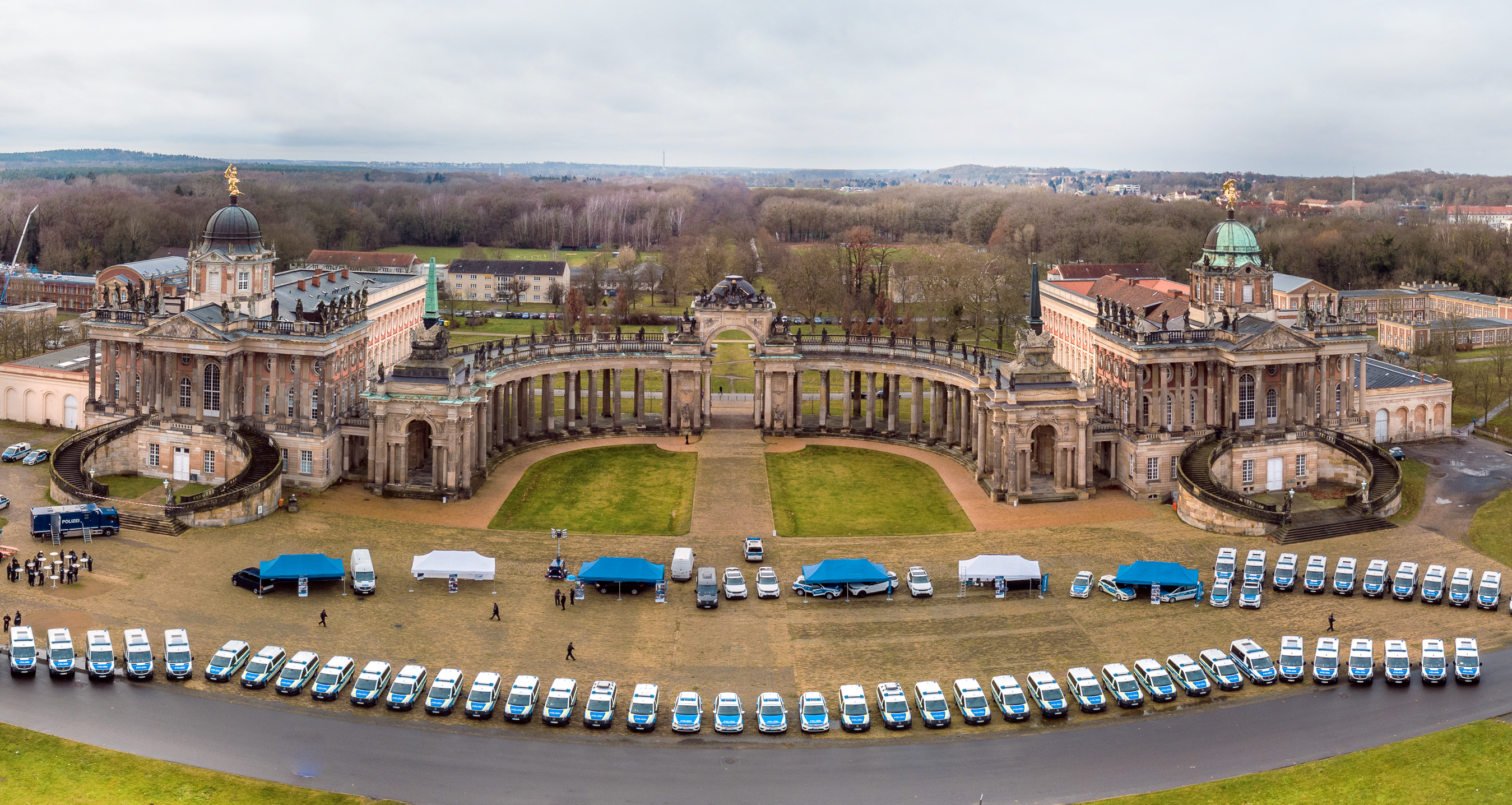 Vogelperspektive auf das Potsdamer Schloss Sanssouci. Im Vordergrund Fahrzeuge der Bundespolizei.