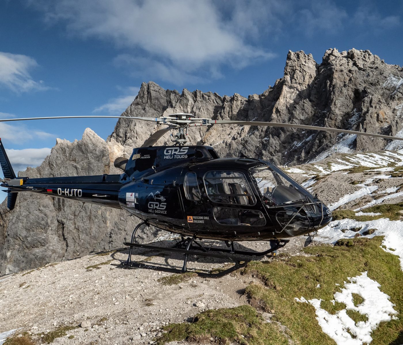 Ein Helikopter steht auf dem Gipfel eines Berges in den Alpen. Der Helikopter wurde für die Durchführung einer Schweremesskampagne angemietet.